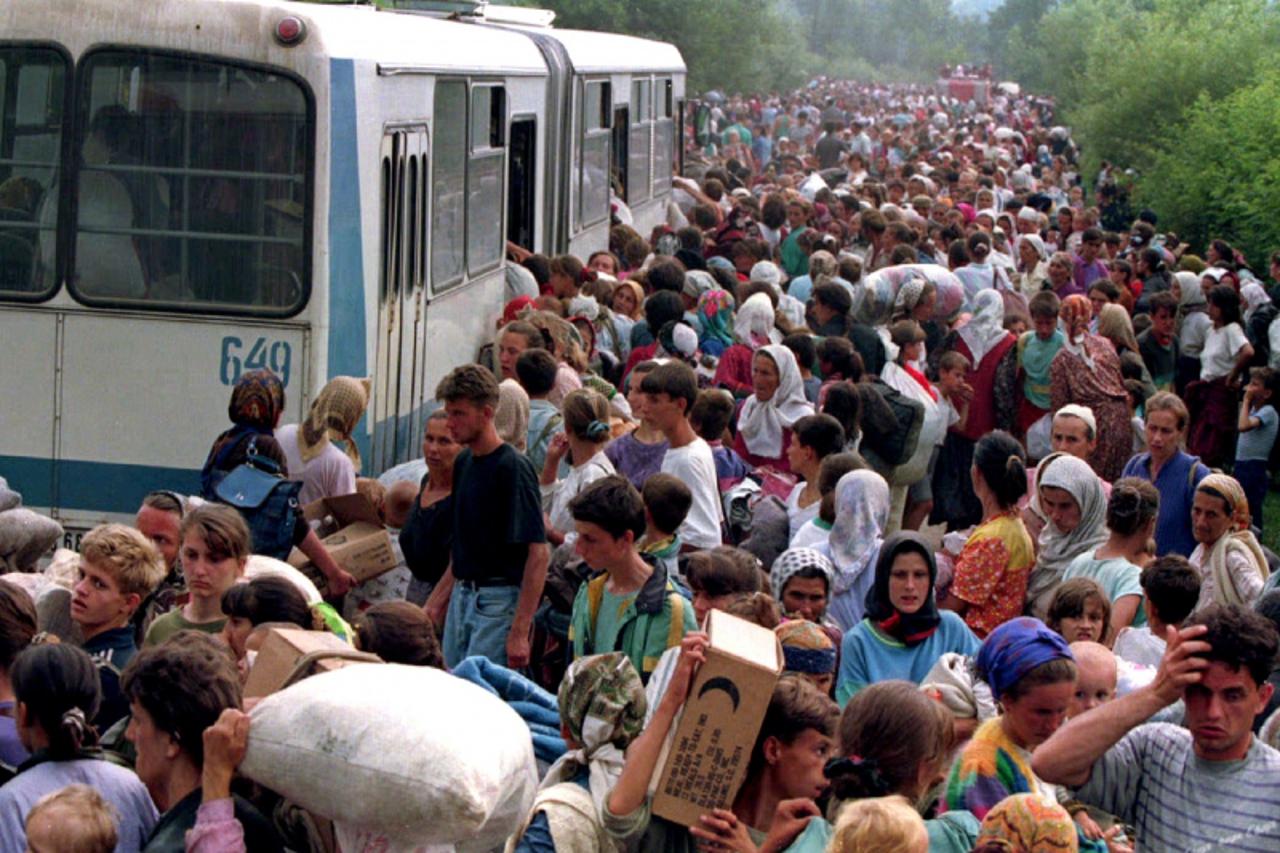 'File picture shows around 10,000 refugees from Srebrenica boarding buses at a camp outside the UN base at Tuzla airport, July 14, 1995. Bosnian Serb general Ratko Mladic made a throat-slitting gestur