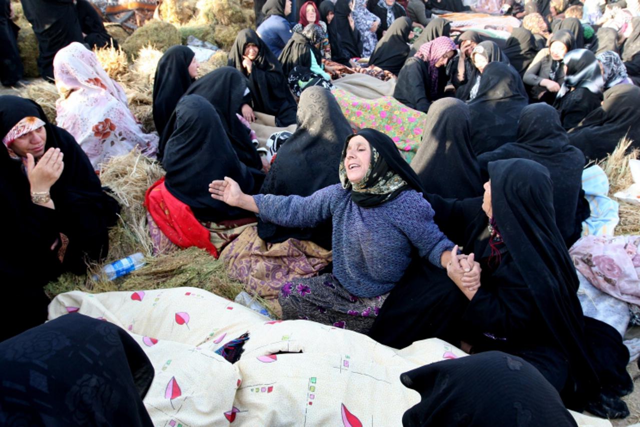 'Iranians mourn over the covered bodies of loved ones in the village Baje-Baj, near the town of Varzaqan, on August 12, 2012, who were killed in twin earthquakes that hit northwestern Iran on August 1