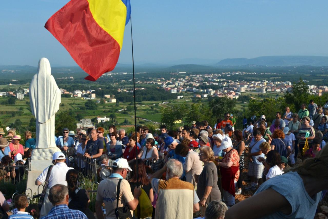 'Catholic pilgrims kneel around a statue of Virgin Mary, overseeing the area around a pilgrimage site near the Southern-Bosnian town of Medjugorje on June 25, 2012. The Virgin Mary is said to have app