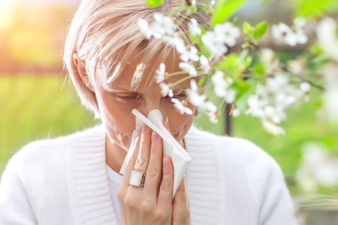 Woman sneezing in the blossoming garden