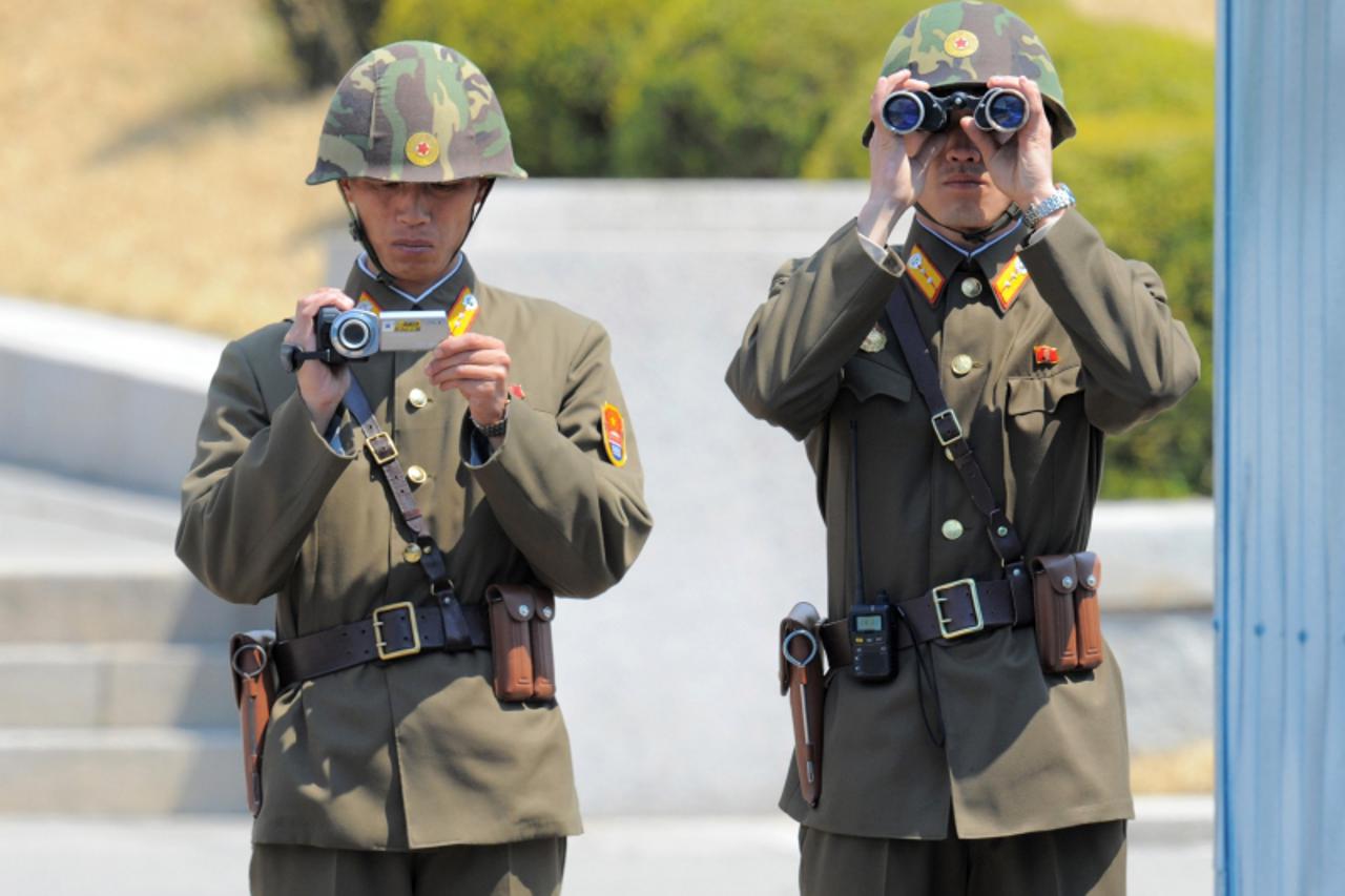 'A North Korean soldier films the crowd as his colleague watches through binoculars while Australian Prime Minister Julia Gillard and her partner Tim Mathieson visit the truce village of Panmunjom in 